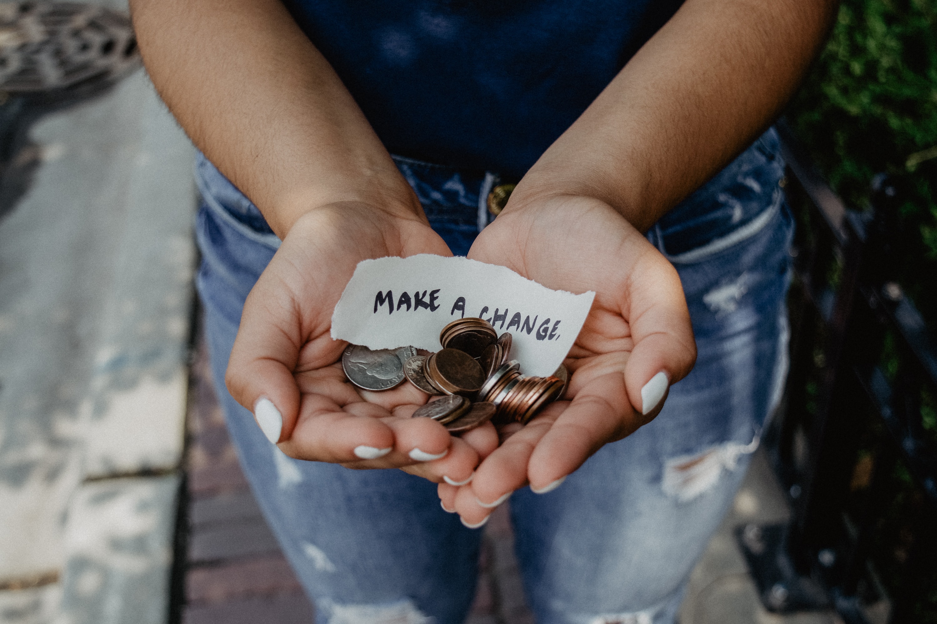 Person holding coins in her hand with a sign that says make a change